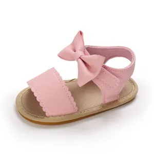 Dettaglio di sandalo rosa per neonata con fiocco in pelle e bordi a forma di smerlo