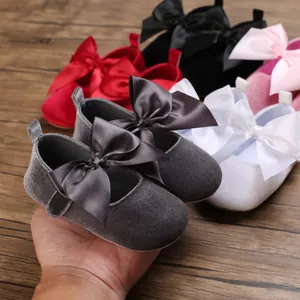 Vue détaillée de chaussures de princesse en velours pour bébé avec un nœud en satin.