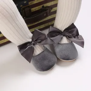Détail macro de chaussures princesse bébé en velours gris avec grands nœuds satin