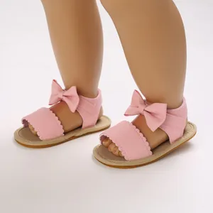 Dettaglio di sandali rosa per neonata con fiocco e bordo smerlato per l'estate