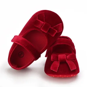 Detailansicht von roten Samt-Babyschuhen mit weicher Sohle und einer dekorativen Schleife