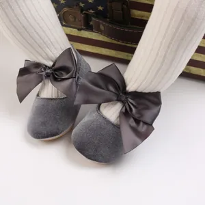 Détail de chaussures de princesse en velours gris pour bébé avec nœuds et semelles souples