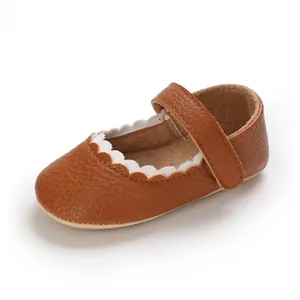 Nahaufnahme von braunen Baby-Mary-Jane-Schuhen aus Leder mit weißen Wellenrand-Details