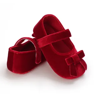 Nahaufnahme roter Samt-Babyschuhe mit Schleifenakzent und weicher rutschfester Sohle