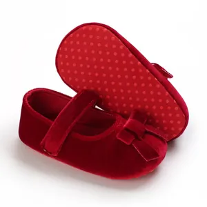 Detaillierte Nahaufnahme roter Baby-Samtschuhe mit rutschfester weicher Sohle und Schleife.