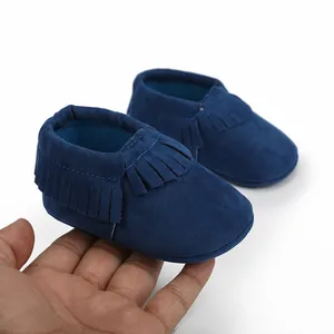 Nahaufnahme von dunkelblauen Wildleder-Babyschuhen mit Fransen für Neugeborene-Modell.