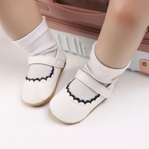 Detailansicht der weißen Baby-Prinzessinenschuhe mit schwarzem Wellenrand und weicher Sohle