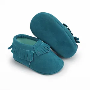 Nahaufnahme von petrolfarbenen Wildleder-Babyschuhen mit weichen, stilvollen Fransen.