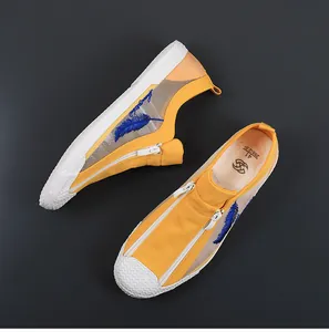 Top-down detail shot of breathable yellow and white mesh casual shoes with blue feather embroidery
