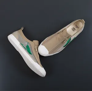 Detailed view of breathable khaki mesh sneakers with green leaf embroidery and zipper.