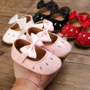 Detalle de zapatos de gateo para niña con lazo rosa grande y acabado de charol