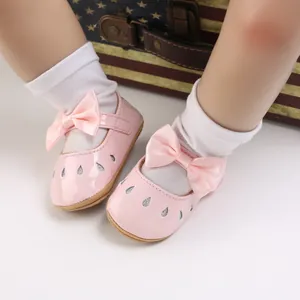Primer plano de zapatos rosas para bebé niña con lazo de satén y detalles de purpurina.