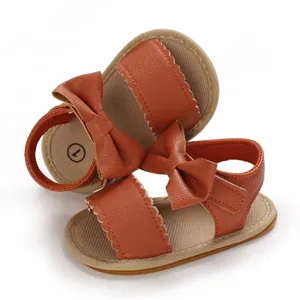 Vista dettagliata dei sandali da bambina color caramello con fiocco e bordi a smerlo