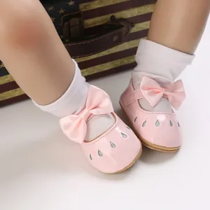 Vista detallada de zapatos de princesa para bebé en charol rosa con un lazo decorativo