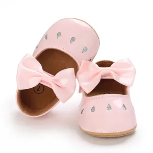 Detalle de zapatos de princesa rosa para bebé niña con lazos de satén y suela blanda