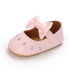 Primer plano de zapato rosa para bebé niña con lazo de raso y gotas de purpurina