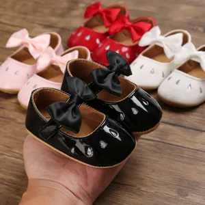 Primer plano de zapatos de bebé negros brillantes con lazo en varios colores disponibles
