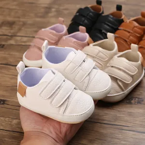 Detailed view of soft white baby walking shoes with adjustable dual strap fasteners