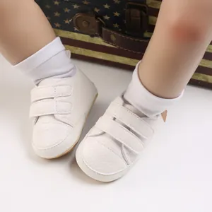 Macro view of white soft sole baby walker shoes with double velcro straps on infant feet