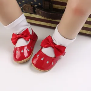 Primer plano de zapatos de princesa rojos para bebé con un lazo y gotas plateadas