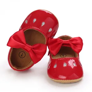 Zapatos rojos de bebé estilo Mary Jane con lazo y purpurina sobre fondo blanco