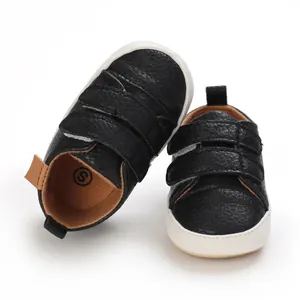 Detail of black faux leather baby walking shoes with white soft soles and Velcro straps