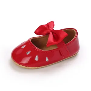 Detalle de zapatos rojos de charol para bebé niña con un gran lazo de satén de color rojo
