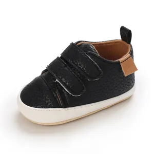 Close-up of black pebbled faux leather baby walking shoe with double velcro straps
