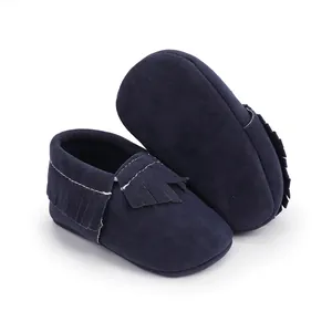 Detail von dunkelblauen Wildleder Babyschuhen mit Fransen und weißen Nähten.