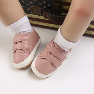 Close-up view of pink soft-soled baby walker shoes featuring velcro straps for infants