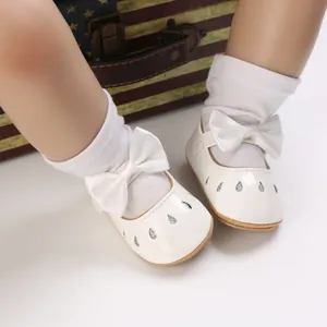 Primer plano de zapatos blancos de princesa para bebé con lazos decorativos