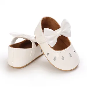 Primer plano de zapatos blancos para bebé con lazo de satén y detalles de purpurina