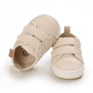 Close-up detail of cream baby walking shoes featuring soft soles and dual velcro straps