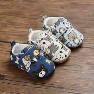 Soft-sole infant walking shoes with various cartoon animal patterns on a wood surface background