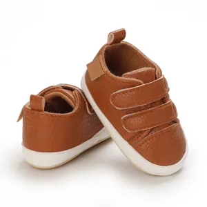 Detail view of brown faux leather baby shoes with white soles and velcro straps