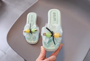 Gros plan de sandales fille vert menthe avec nœud en maille et perles décoratives.