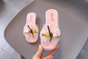 Gros plan de pantoufles roses pour filles avec de grands nœuds en résille et perles.