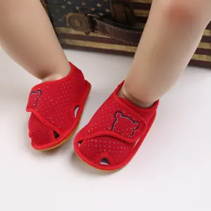 Close-up of red infant sandals with bear patch and breathable soft sole for summer
