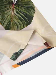Detalle de camisa de playa para hombre con estampado de hojas y costuras de dobladillo finas.