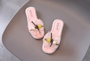 Gros plan de sandales roses pour filles avec fleurs en dentelle délicates et détails perles.