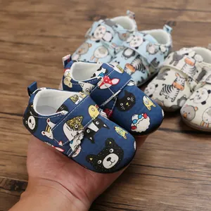 Detailed view of dark blue infant walking shoes with cute cartoon animal patterns.