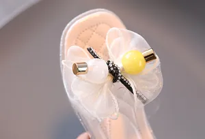 Gros plan sur le nœud décoratif en voile et les perles d'une sandale d'été pour fille