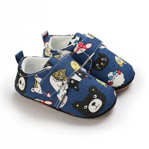 Detailed macro view of cartoon animal prints and velcro on navy baby pre-walker shoes