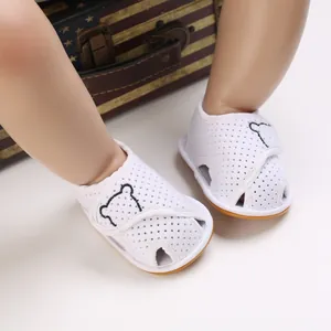 Detailed close-up of white baby summer sandals with cartoon bear embroidery and soft soles