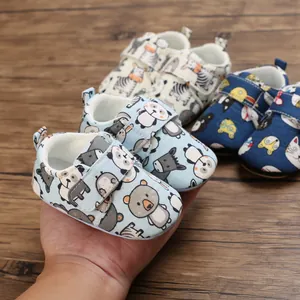 Close-up of soft-soled baby shoes with cartoon animal patterns and velcro straps.