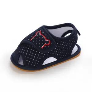 Detail of baby sandals featuring navy blue polka dots and a red bear embroidery