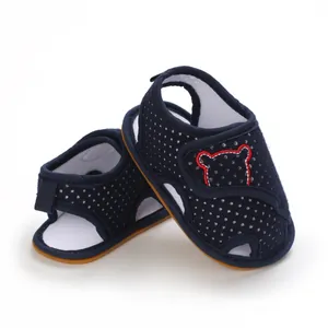 Detail of navy blue baby sandals featuring white polka dots and a cartoon bear