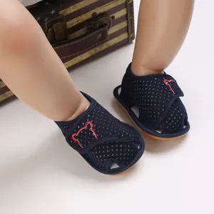 Detailed view of navy blue baby sandals featuring red bear embroidery on doll's feet