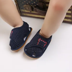 Close-up of dark blue toddler sandals featuring white polka dots and bear embroidery detail
