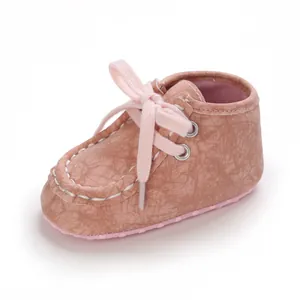 Nahaufnahme eines rosa Lauflernschuhs für Babys mit Schnürung und Risslederoptik.